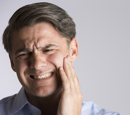 Man in his 40s with a headache and toothache holding the side of his face