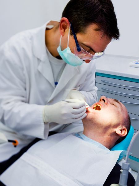 A patient lying back, relaxed in a dental chair, as the dentist uses a tool in the patient's mouth